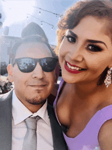 a man and a woman are posing for a picture and the woman is wearing a purple top