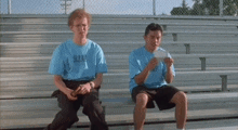 two men are sitting on a bleacher wearing blue shirts that say ' u.s.a.c. ' on them