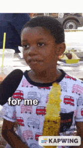 a young boy is eating corn on the cob and talking into a microphone while wearing a shirt with buses on it .