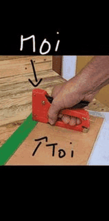 a person is using a stapler to staple a piece of wood on a table .