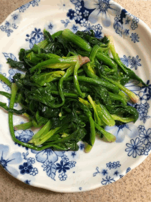 a blue and white plate filled with spinach and flowers