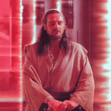 a man with long hair and a beard is standing in a red room