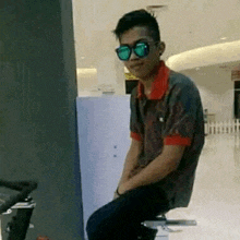 a young man wearing sunglasses is sitting on a stool in a store .