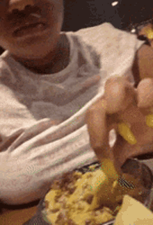 a person with yellow nails is eating a meal with chopsticks