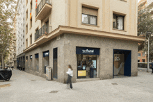 a woman walks past a aural store on the corner of a building