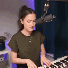 a woman in a green shirt is playing a keyboard in front of a microphone that has the number 21 on it