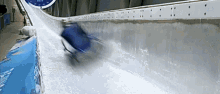 a person in a blue sled is going down a snow covered track