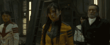 a woman in a yellow jacket is standing in a room with other people