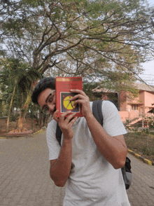 a man covering his face with a book that says harry potter and the philosopher 's stone