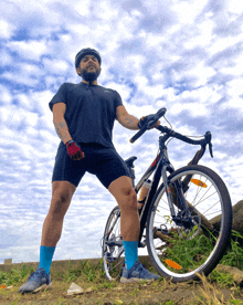 a man wearing a helmet and shorts stands next to a bike