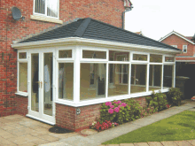 a brick house with a black roof and a white conservatory on the side