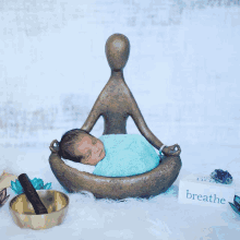 a baby wrapped in a blue blanket is sleeping in a bowl next to a box that says breathe