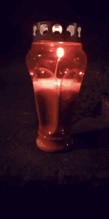 a red candle is lit up in the dark and looks like a heart