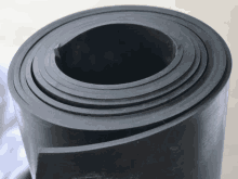 a roll of black rubber is rolled up on a white surface