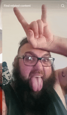 a man with glasses and a beard is making a horns sign with his hand