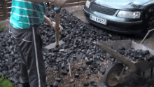 a man is digging in a pile of coal next to a car with a license plate that says b1884965