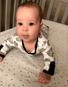 a baby wearing a hedgehog outfit is crawling on a bed