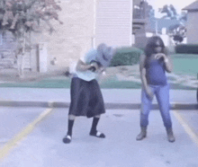 a man and a woman are dancing in a parking lot in front of a building .