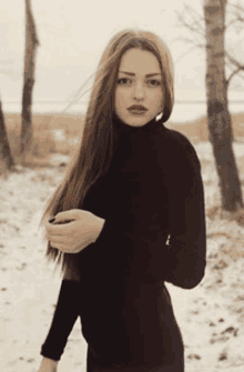 a woman with long hair is wearing a black turtleneck sweater and red lipstick .