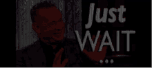 a man in a suit and tie is behind a sign that says just wait