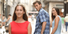 a woman in a red dress looks at a man in a blue plaid shirt