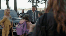 a man in a suit and tie stands in front of a jeep with a license plate that says 206