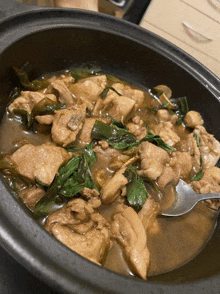 a bowl of chicken stew with spinach and mushrooms with a spoon in it