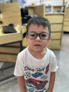 a young boy wearing glasses and a drive fast shirt