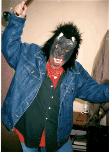 a man wearing a mask and a denim jacket is holding a stick