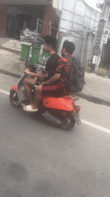 two men are riding a scooter on a street