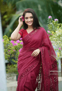 a woman in a maroon saree is smiling and holding a flower in her hand