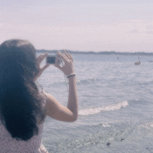 a woman is taking a picture of the ocean