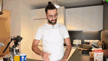 a man in a white apron is cooking in a kitchen with a bottle of french bread flour on the counter