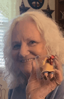 a woman is smiling while holding a small doll