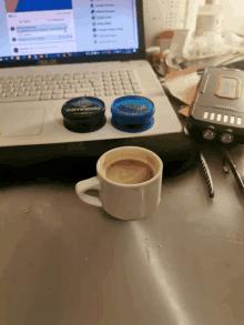 a cup of coffee sits on a desk in front of a laptop computer