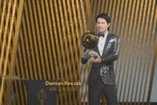 a man in a tuxedo is holding a trophy that says damian recek