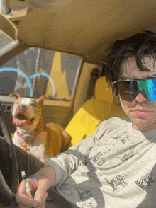 a man wearing sunglasses is sitting in a car with a dog behind him