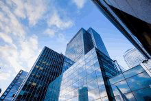 looking up at a skyscraper with a blue sky and clouds behind it