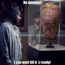 a man is looking at a kebab in a glass case with the caption no worries i can wait till it s ready