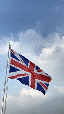 a british flag is flying in the wind against a cloudy blue sky