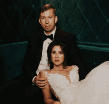 a bride and groom sit on a green couch