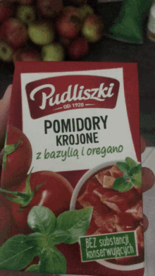 a person is holding a box of pudliszki tomato soup