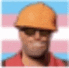 a blurry picture of a man wearing a hard hat , sunglasses and a red shirt .