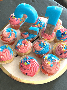 a tray of cupcakes with pink and blue frosting and a number 2 candle