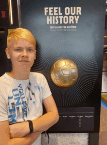 a boy is standing in front of a sign that says feel our history