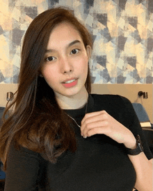 a young woman wearing a black shirt and a necklace is taking a selfie .