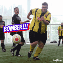 a man in a yellow and black jersey kicks a soccer ball in front of a sign that says bomber !!!