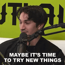 a man sitting in front of a microphone with the words " maybe it 's time to try new things "