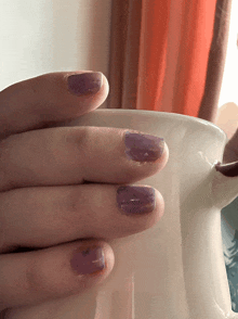 a close up of a person 's nails holding a cup