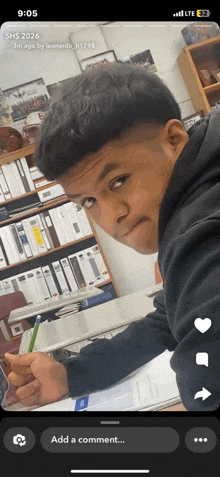 a phone screen shows a photo of a boy sitting at a desk